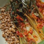 Appetizing dish of grains, greens, and spicy kimchi on rustic tableware.